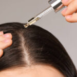 Woman applying hair oil to the scalp with a dropper