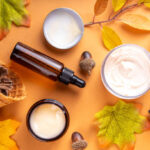 Autumn skincare products with fall leaves on a beige background