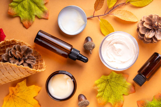 Autumn skincare products with fall leaves on a beige background