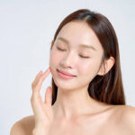 Woman with dewy skin applying skincare as part of a Korean beauty routine