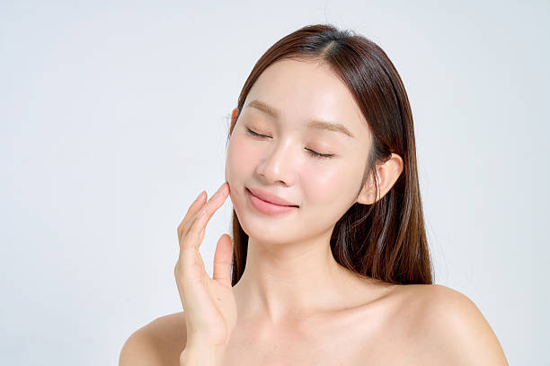 Woman with dewy skin applying skincare as part of a Korean beauty routine